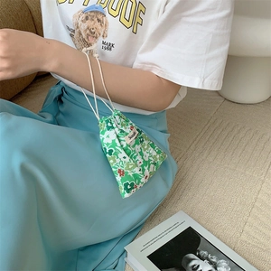 Close-up of floral drawstring bag held by model, featuring light green fabric and white flowers