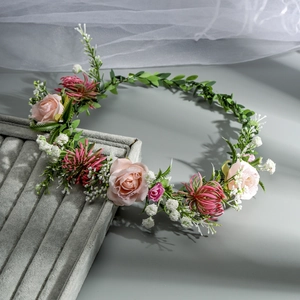 Detail shot of a floral bridal headpiece with pink roses and green leaves on a velvet tray