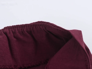 Detailed macro view of burgundy high-waisted trousers with pleated elastic waistband