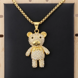 Macro detail of a golden teddy bear pendant with clear rhinestones on a black background