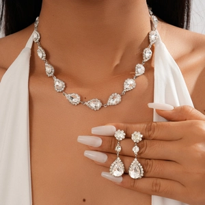 Close-up of teardrop crystal necklace set and matching drop earrings on a model