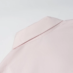 Gros plan du col de chemise rose montrant les coutures et la texture lisse du tissu