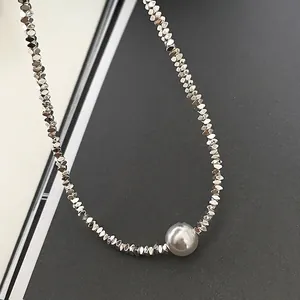 Minimalist silver beaded necklace with large round pearl pendant on grey background