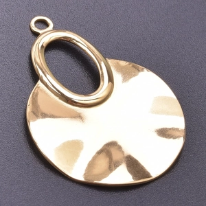 Detailed view of irregular wavy gold pendant with textured metal surface on grey background