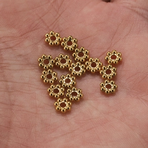 Macro shot of gold stainless steel snowflake spacer beads held in palm for jewelry DIY