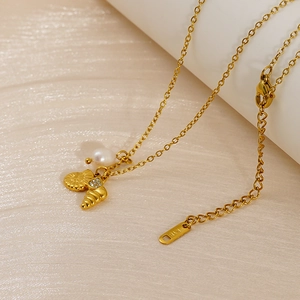 Close-up of gold shell and pearl pendant showing K18 hallmark and zircon details