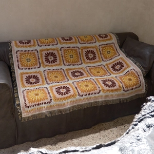 Detail of bohemian knitted sofa blanket with geometric floral patterns and fringe edges