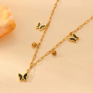 Close-up of golden chain necklace featuring black butterfly pendants and gold beads
