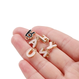 Golden alloy alphabet charms spelling baby with black and white enamel in a palm