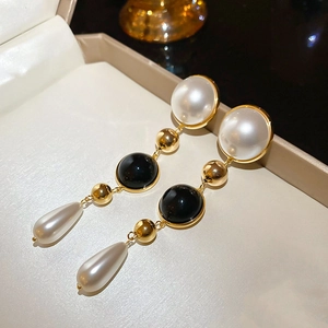 Detail view of 18k gold plated drop earrings with white pearls and black circular charms