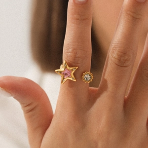 Gold star-shaped open ring with pink zircon and white crystal on female hand
