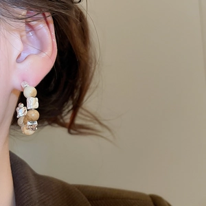 Détail de boucles d'oreilles en C avec perles d'oeil de tigre et métal argenté irrégulier