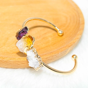 Detail of natural amethyst and citrine stones set on a gold-plated open C-shaped cuff