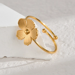 Elegant gold open bangle with a textured five-petal flower and polished beads on display