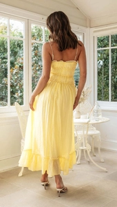 Détail d'une robe longue jaune dos nu avec texture plissée dans un cadre ensoleillé