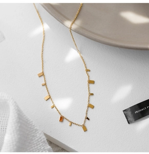 Detail shot of a gold-plated O-chain necklace with small rectangular metal charms