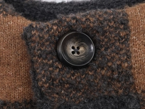 Close-up of thick plaid knit fabric with a marble texture button on a winter coat