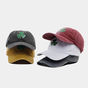 Dettaglio di cappelli da baseball in cotone lavato impilati con ricamo a trifoglio verde