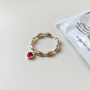 S925 sterling silver twist ring with a red heart gemstone pendant on a cream background