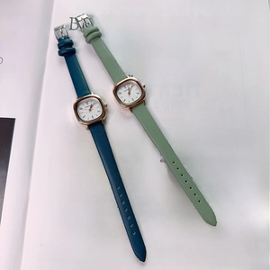 Close-up of vintage square quartz watches with navy and green leather straps on a magazine