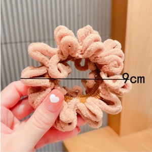 Detail view of pink plush scrunchie showing 9cm diameter and fluffy velvet texture