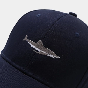 Close-up of shark embroidery on navy blue cotton canvas baseball cap with fine texture