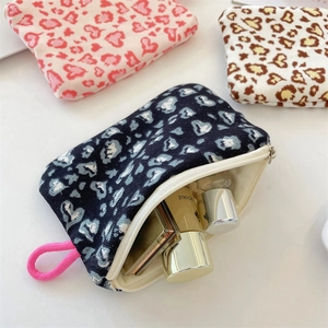 Detail of printed canvas cosmetic pouch showing leopard heart pattern and top zipper