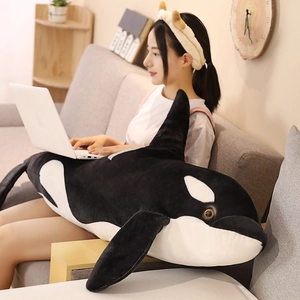 Large black and white orca plush toy being used as a comfortable pillow on a sofa