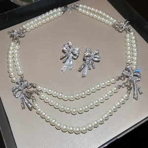 Close-up of pearl necklace and bow earrings with rhinestones in a gift box