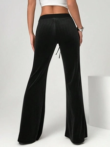 Close-up back view of velvet flared trousers showing the glossy texture and sleek fit