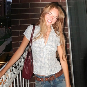 Detail of blue and white plaid shirt paired with blue jeans and a burgundy bag