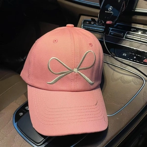 Close-up of a pink baseball cap with detailed silver bow embroidery and twill texture