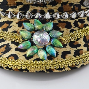 Close-up of leopard captain hat with silver studs, gold braid, and crystal floral detail
