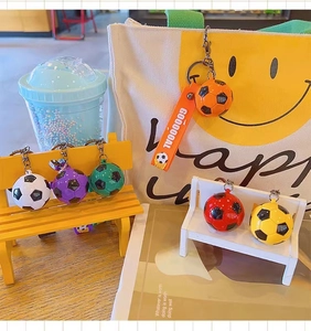 Colorful soccer ball keychains displayed on a wooden surface with a canvas tote bag