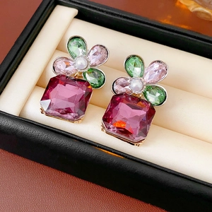 Detailed macro view of vintage square purple gem earrings with floral pearl accents