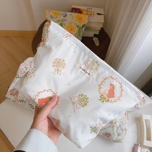Detail of floral cotton makeup bag with simple wish label held in a cozy home setting