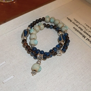 Detail of double-layer beaded bracelet with ceramic stones in dark blue and earthy tones