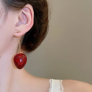 Gros plan d'un mannequin portant des boucles d'oreilles cerise avec des perles en résine rouge
