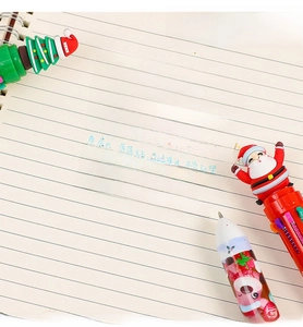 Close-up of 10-color Christmas ballpoint pen with Santa and tree toppers on a notebook