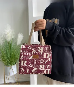 Détail du sac à déjeuner en toile bordeaux avec imprimé lettres et anses larges