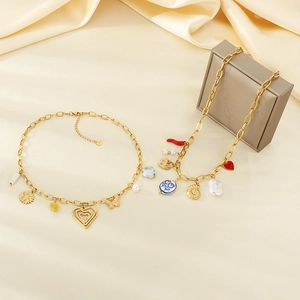 Close-up of golden necklaces with sunflower and butterfly charms on beige silk background