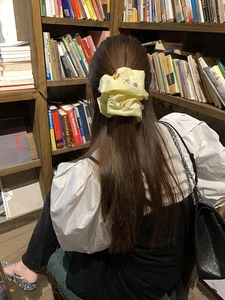 Dettaglio di un elastico giallo con perline floreali colorate indossato in libreria