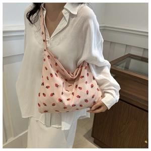 Detail of pink corduroy tote bag with strawberry pattern shown in a lifestyle setting