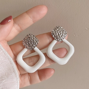 Silver hammered geometric earrings with white square drops shown held in hand