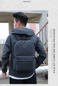 Detail of dark gray canvas backpack featuring diamond patch and front zipper pocket