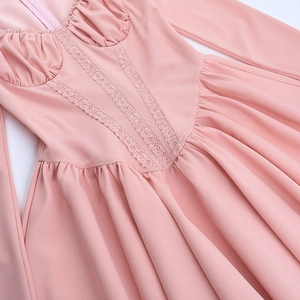 Close-up of V-neck pleats and delicate lace trim on pink long-sleeved dress