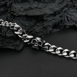 Macro view of stainless steel Cuban link bracelet featuring a central silver skull motif