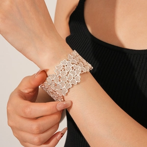 Close-up of wide silver open cuff bracelet featuring an intricate hollow floral pattern