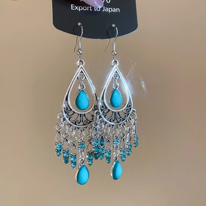 Detailed shot of bohemian silver earrings with turquoise waterdrop stones and tassels