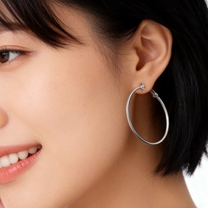 Polished silver metal hoop earrings worn by a model in a close-up side view profile